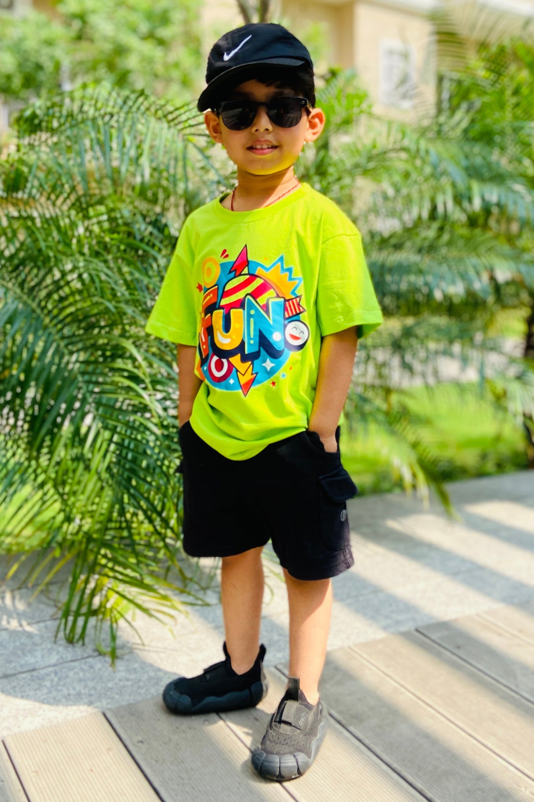 Child wearing a neon green tshirt with colorful graphics and with text FUN on it 
