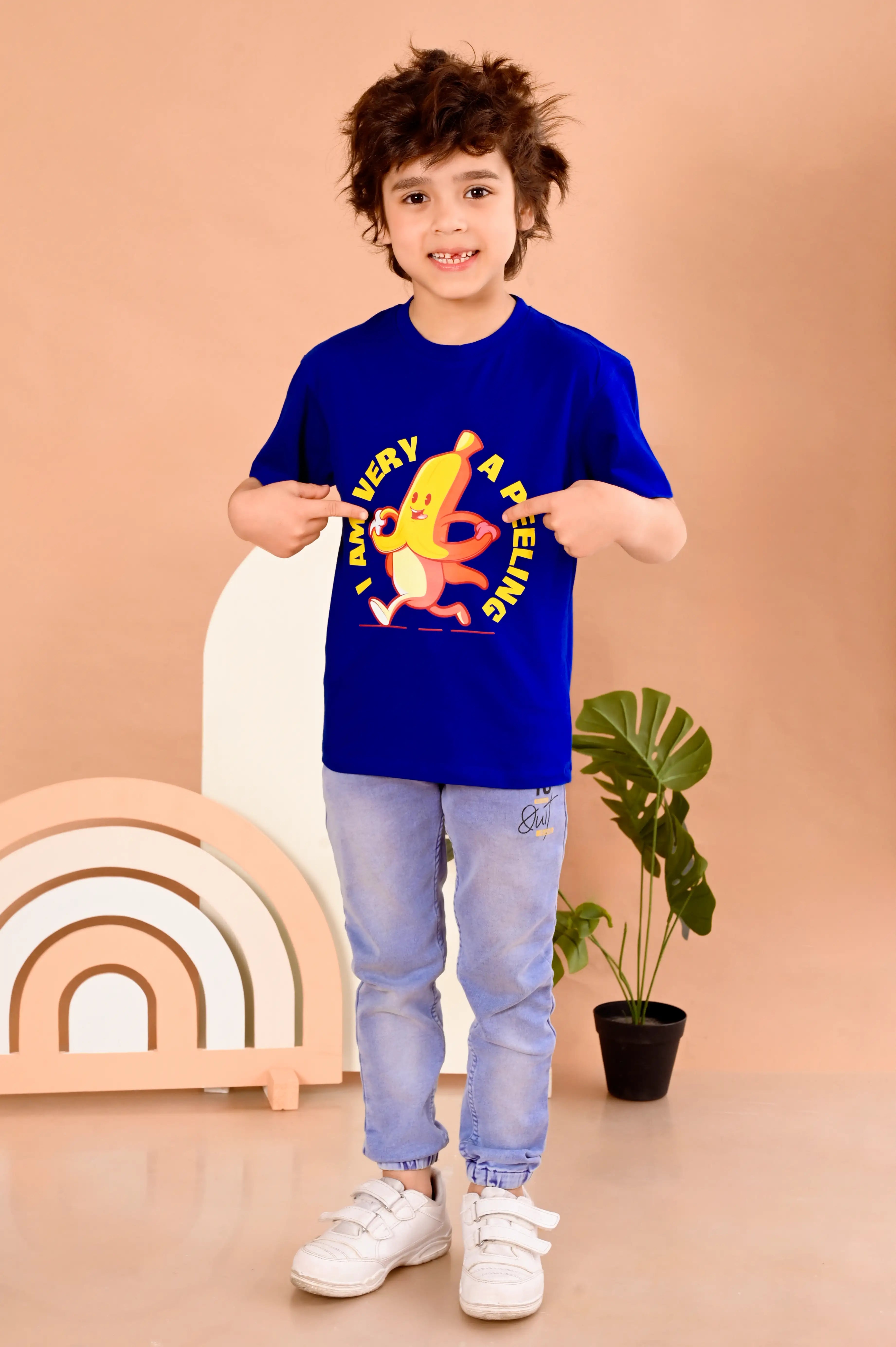 Child wearing a blue t-shirt with a banana graphic with text " i am very a peeling "