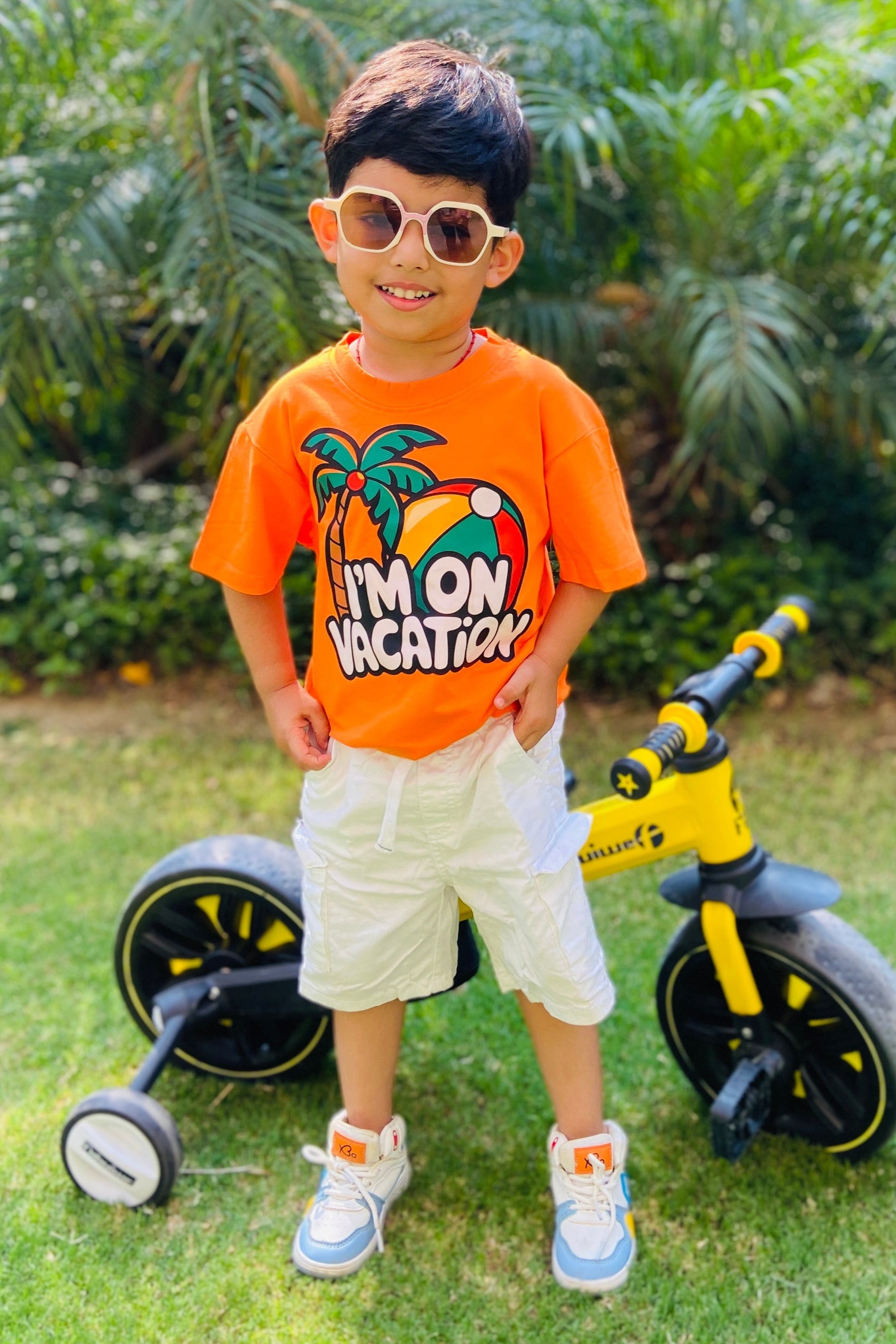 Child wearing an orange t-shirt with a graphic and "I'm on vacation" text.