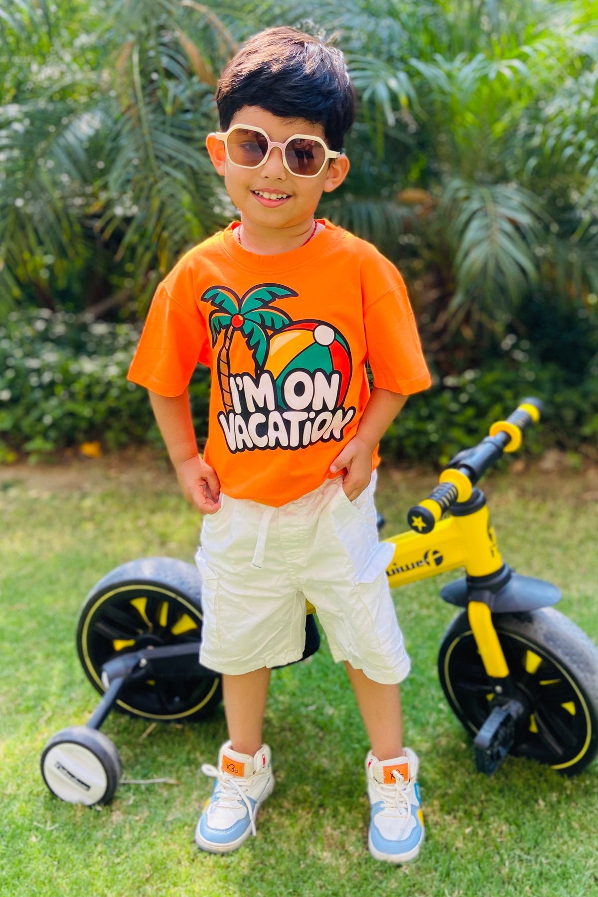 Child wearing an orange t-shirt with a graphic and "I'm on vacation" text.