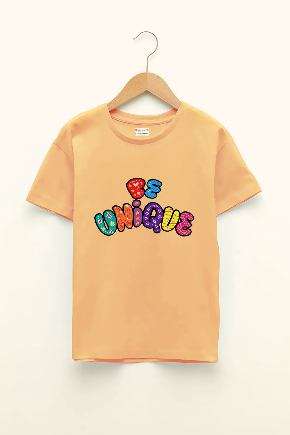 A peach-colored round neck t-shirt with 'BE UNIQUE' printed in colorful letters on the front.