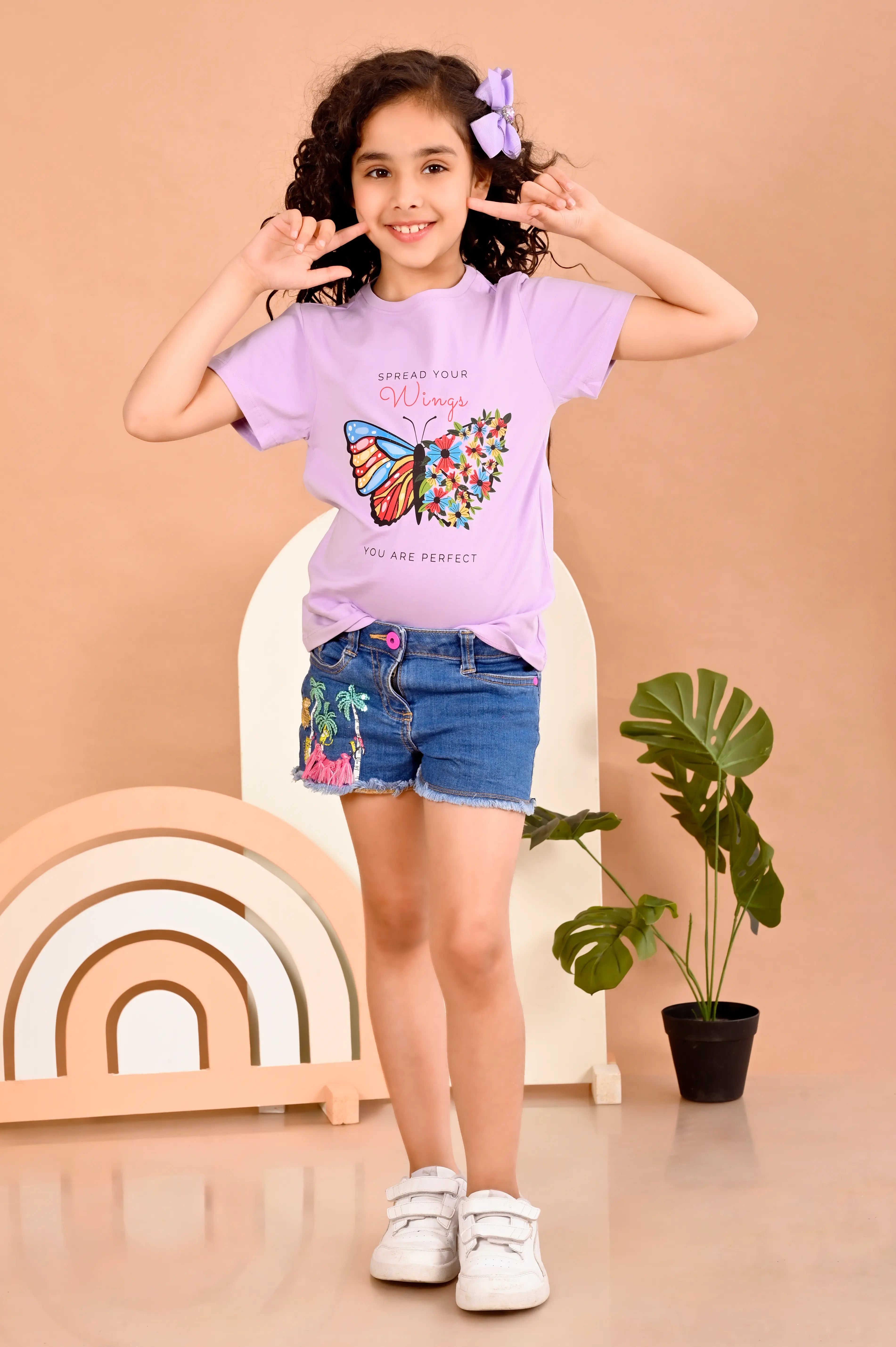 wearing a purple t-shirt with a butterfly design with text spread your wings , you are prefect .