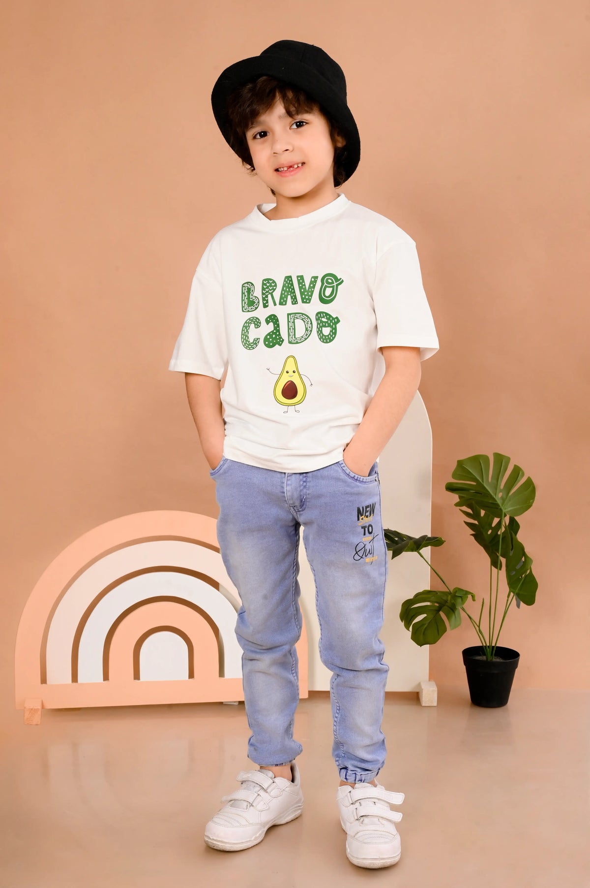 Child wearing a off white t-shirt with 'Bravo Cado' text . 