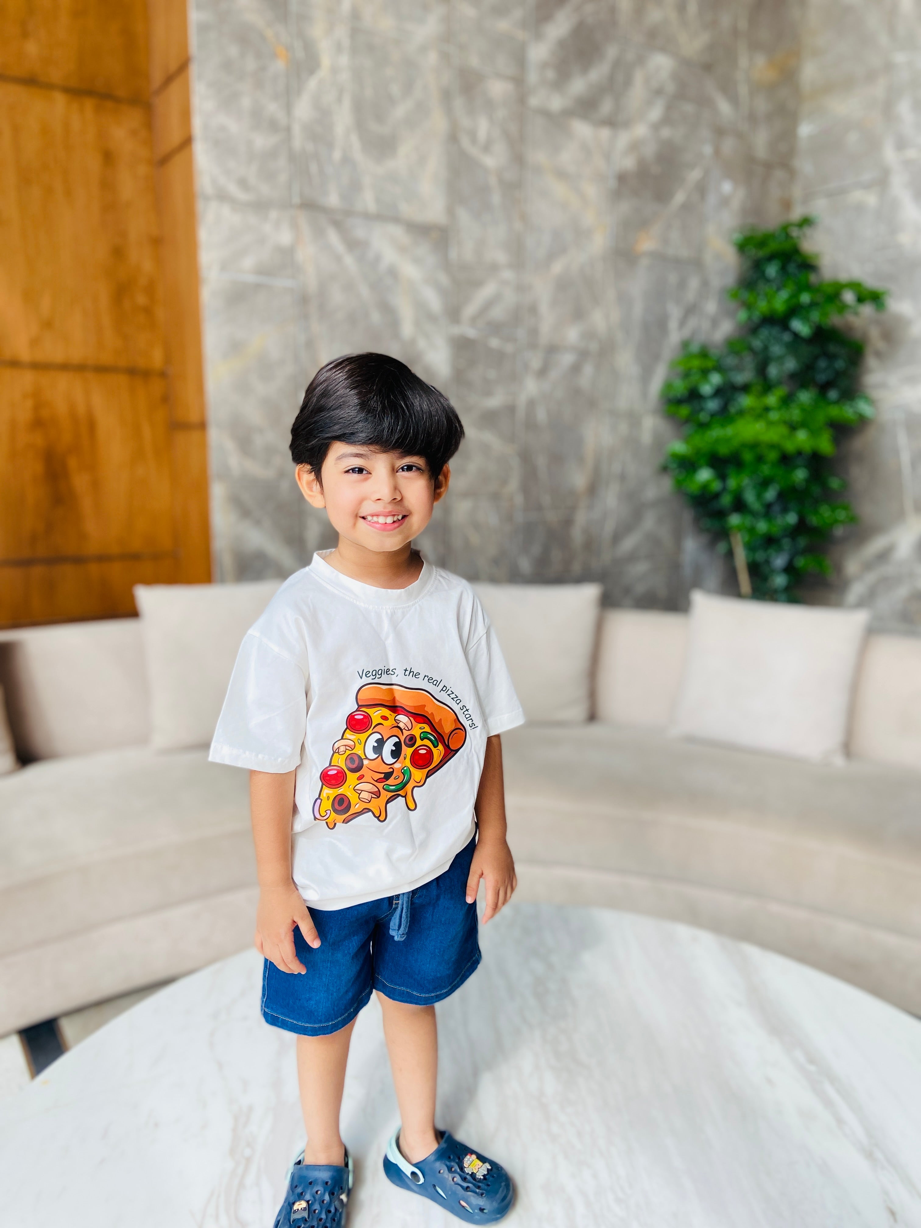 Child wearing a white t-shirt with a pizza design in a living room setting