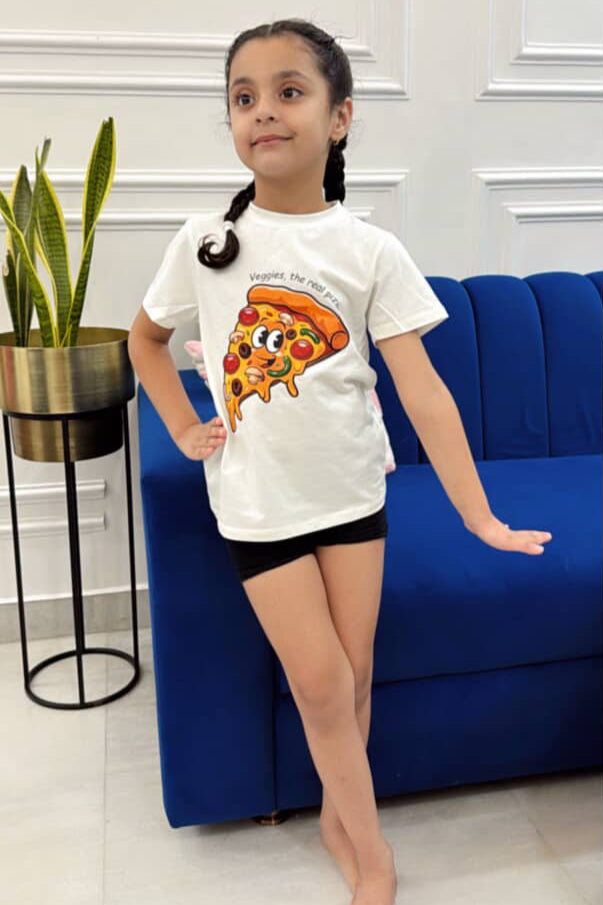 Young girl wearing a white t-shirt with a pizza graphic design in a room with a blue couch and plant.